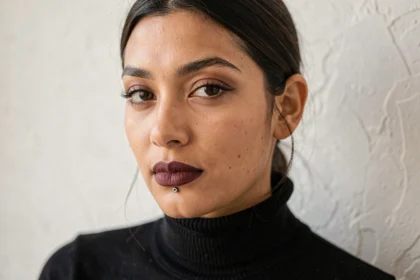 Femme avec un piercing labret et un rouge à lèvres bordeaux mat, portrait éditorial en studio minimaliste